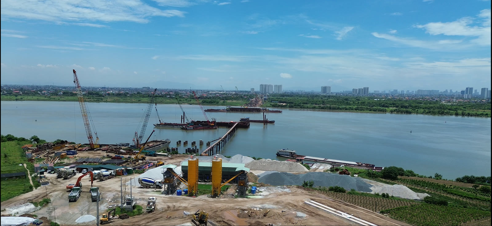 Toàn cảnh công trường cầu Ngọc Hồi phía bờ Hà Nội nhìn từ trên cao, có cần cẩu, trạm trộn bê tông và cầu tạm dẫn ra giữa sông Hồng
