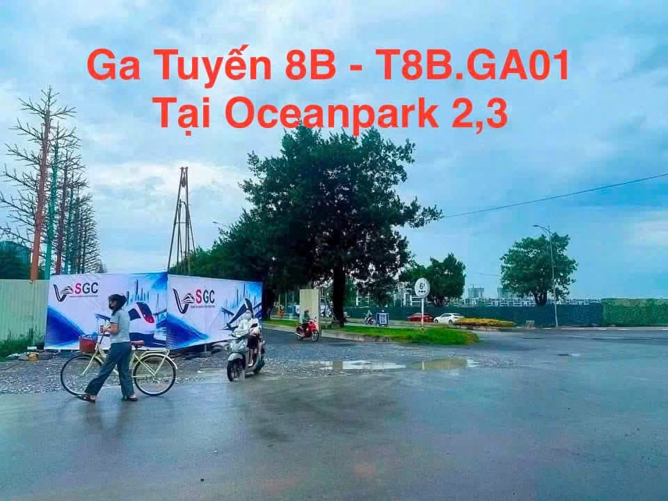 Hàng rào tôn quây khu vực nhà ga metro tuyến 8B mã T8B.GA01 tại ngã tư gần Ocean Park 2 và 3, có người dắt xe đạp và xe máy đi qua