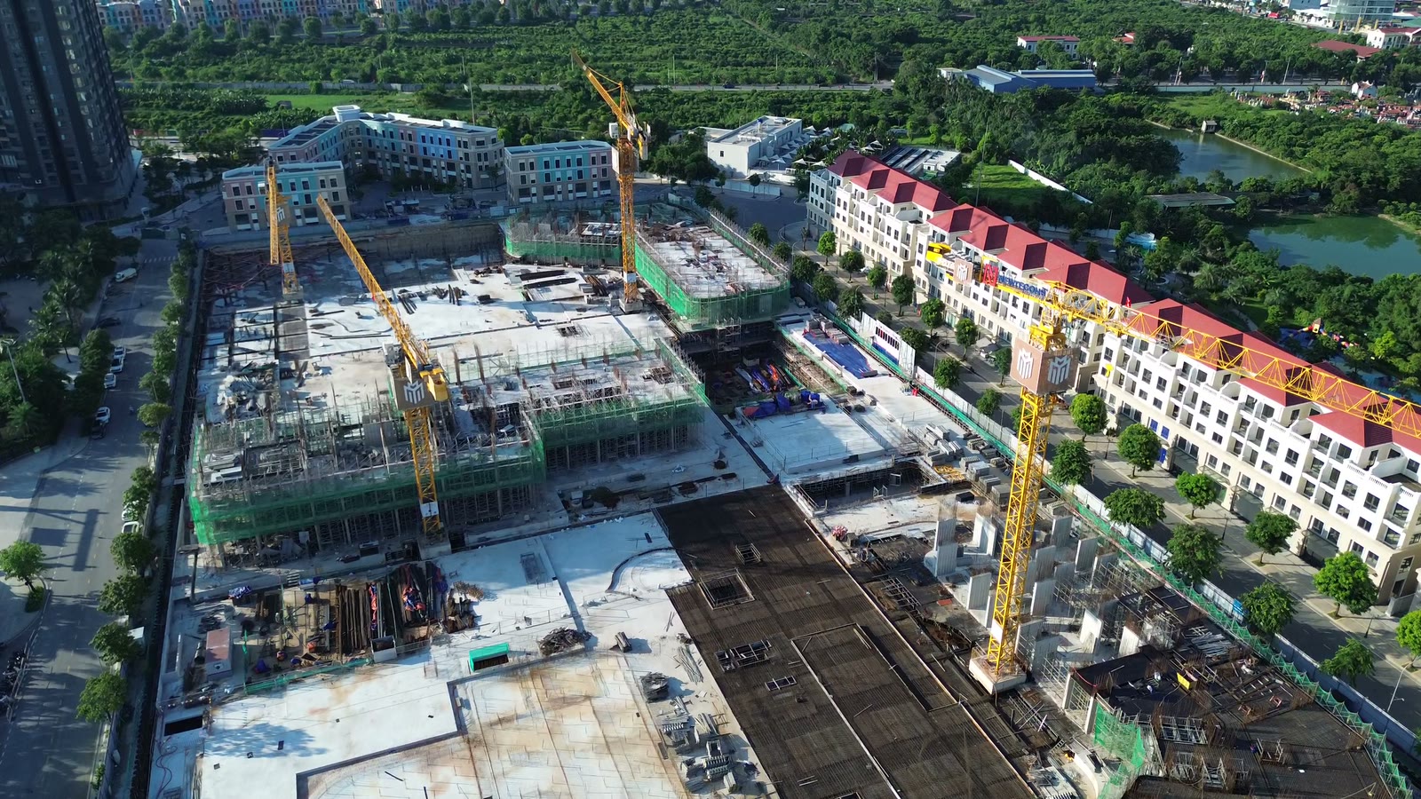 Toàn cảnh công trường Masteri Grand Coast từ trên cao, phần nắp hầm đã đổ bê tông xong, các toà tháp quây lưới xanh đang lên tầng